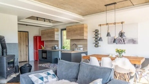 En moderne stue med sofa, spisebord og et køkken i baggrunden.