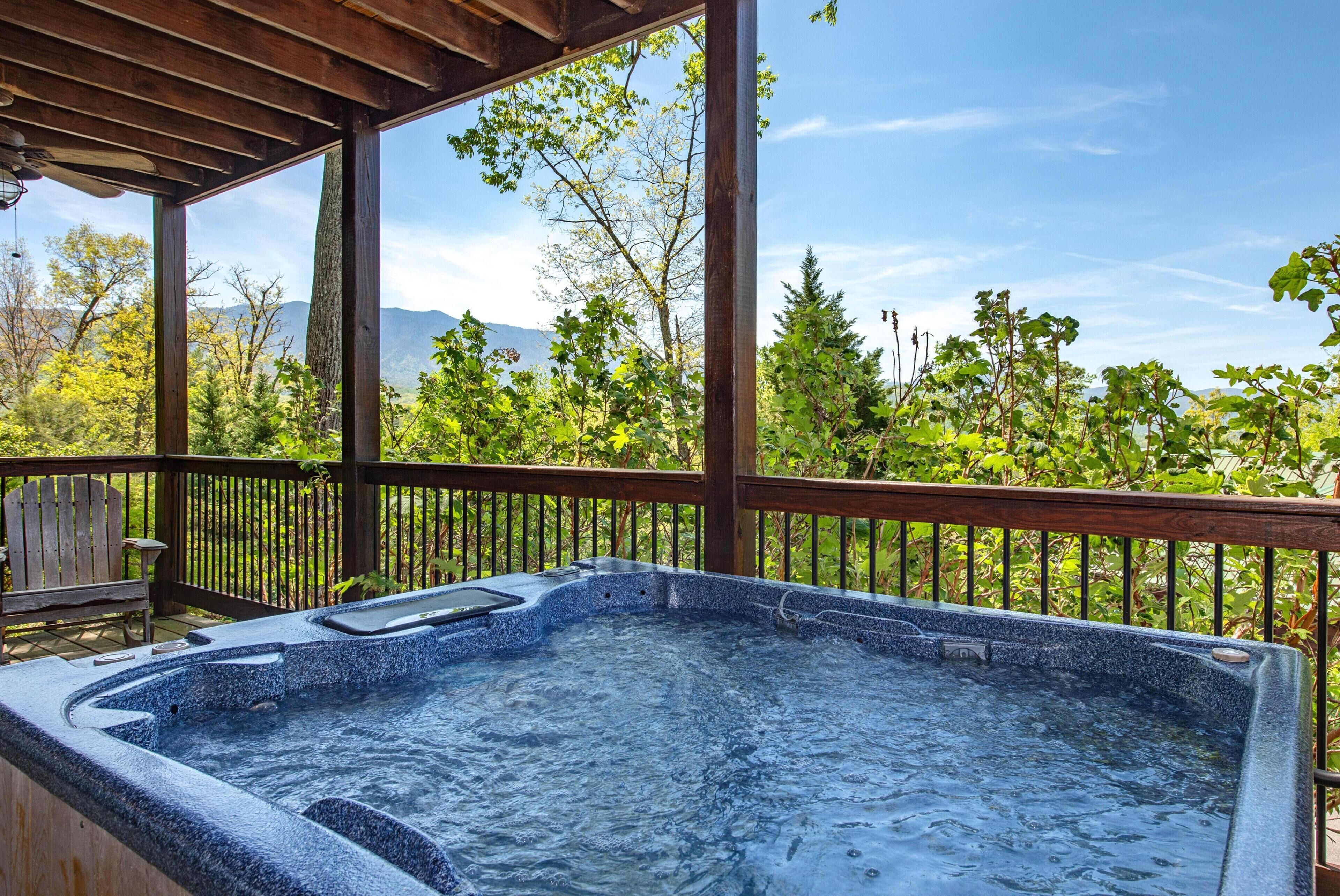 A hot tub under a wooden pergola with a view of trees and mountains.