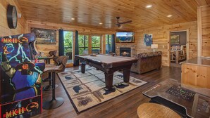 A wooden interior with a pool table, a fireplace, and a bear painting. - Another Day in Bearadise (Gatlinburg)