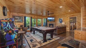 A wooden interior with a pool table, a fireplace, and a bear painting.