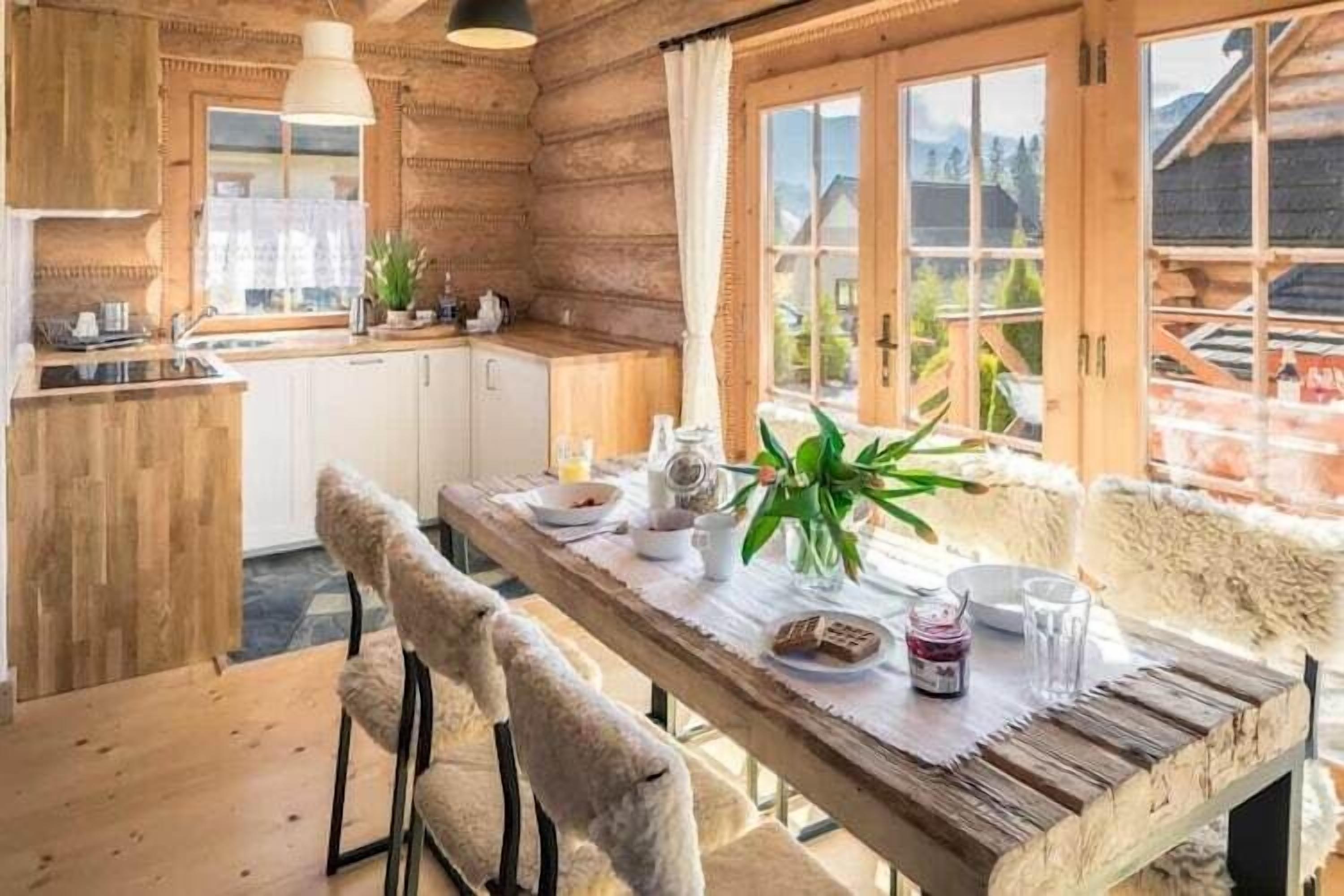 Un intérieur en bois comprenant une table à manger, des chaises et une fenêtre donnant sur des immeubles.