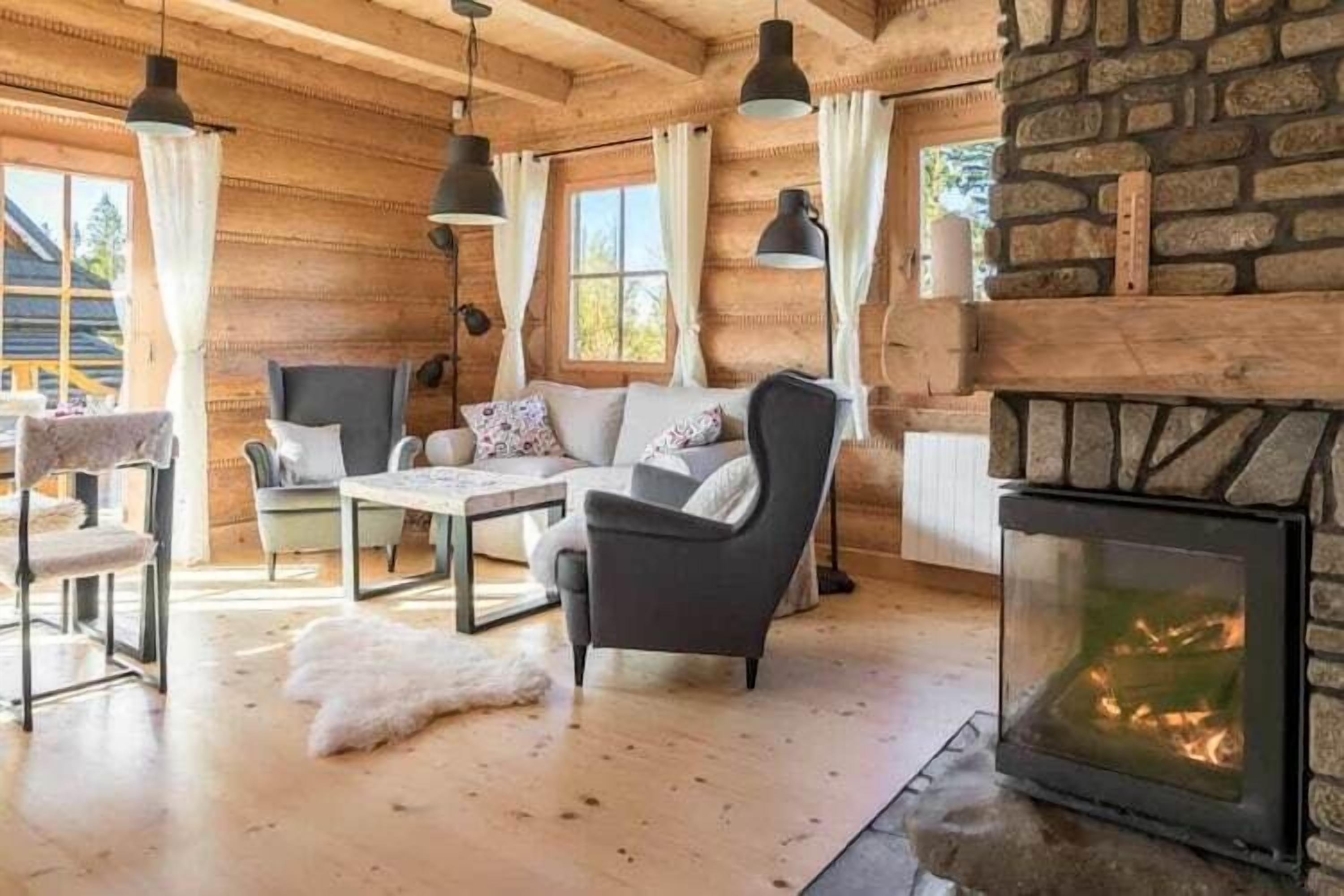L’intérieur d’une cabane en rondins, avec une cheminée, des murs en bois et un coin salon confortable.