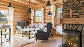A log cabin interior with a fireplace, wooden walls, and a cozy seating area.