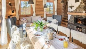 A cozy log cabin interior with a dining table set, a fireplace, and a sofa.