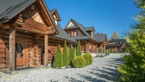 A row of log cabins with a gravel driveway and neatly trimmed bushes.