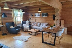 Interior acogedor de una cabaña de madera con un conjunto de sofás, una mesita de centro y una mesa de comedor.