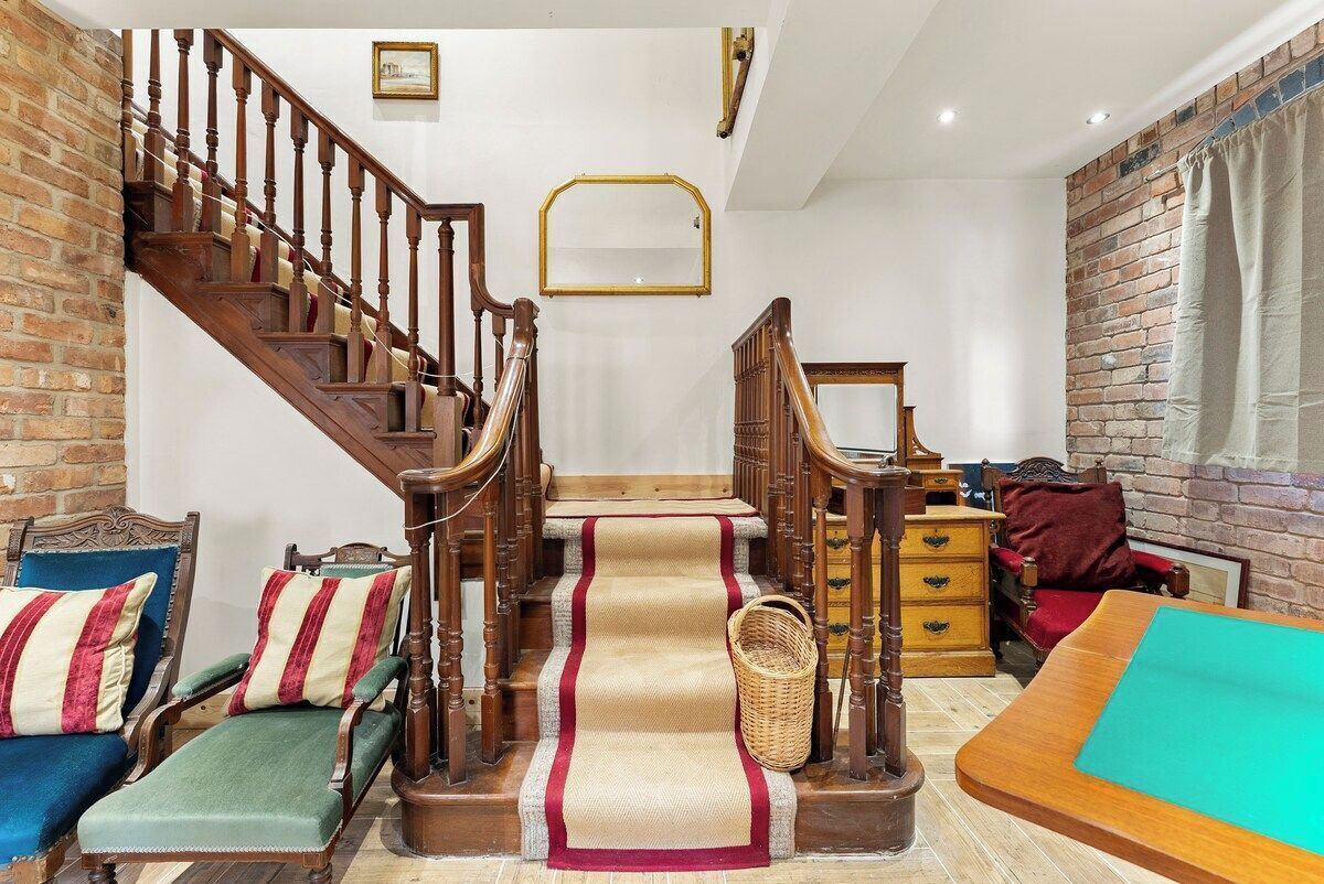A staircase with wooden railings, a red carpet, and a wicker basket.