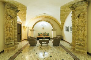 An interior with a mosaic floor, a sofa set, and stone carvings. - Villa del Prete by Casa di Marco (Nardò)
