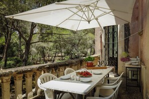 A terrace with a table set for dining, surrounded by chairs, under a large umbrella. - Villa del Prete by Casa di Marco (Nardò)