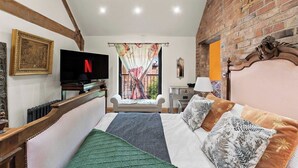 Une chambre à coucher avec un lit, une télévision, une fenêtre avec des rideaux, une petite table et une chaise.