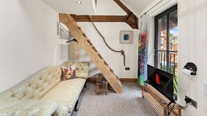 Une pièce avec un canapé, un escalier en bois, une télévision et une fenêtre donnant sur un beau paysage.