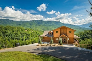 Une cabane en bois avec des fondations en pierre, une véranda et une vue sur des montagnes verdoyantes.