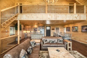 A spacious wooden interior with a dining area, kitchen, and a staircase leading to an upper level. - The Perfect Tenn (Gatlinburg)