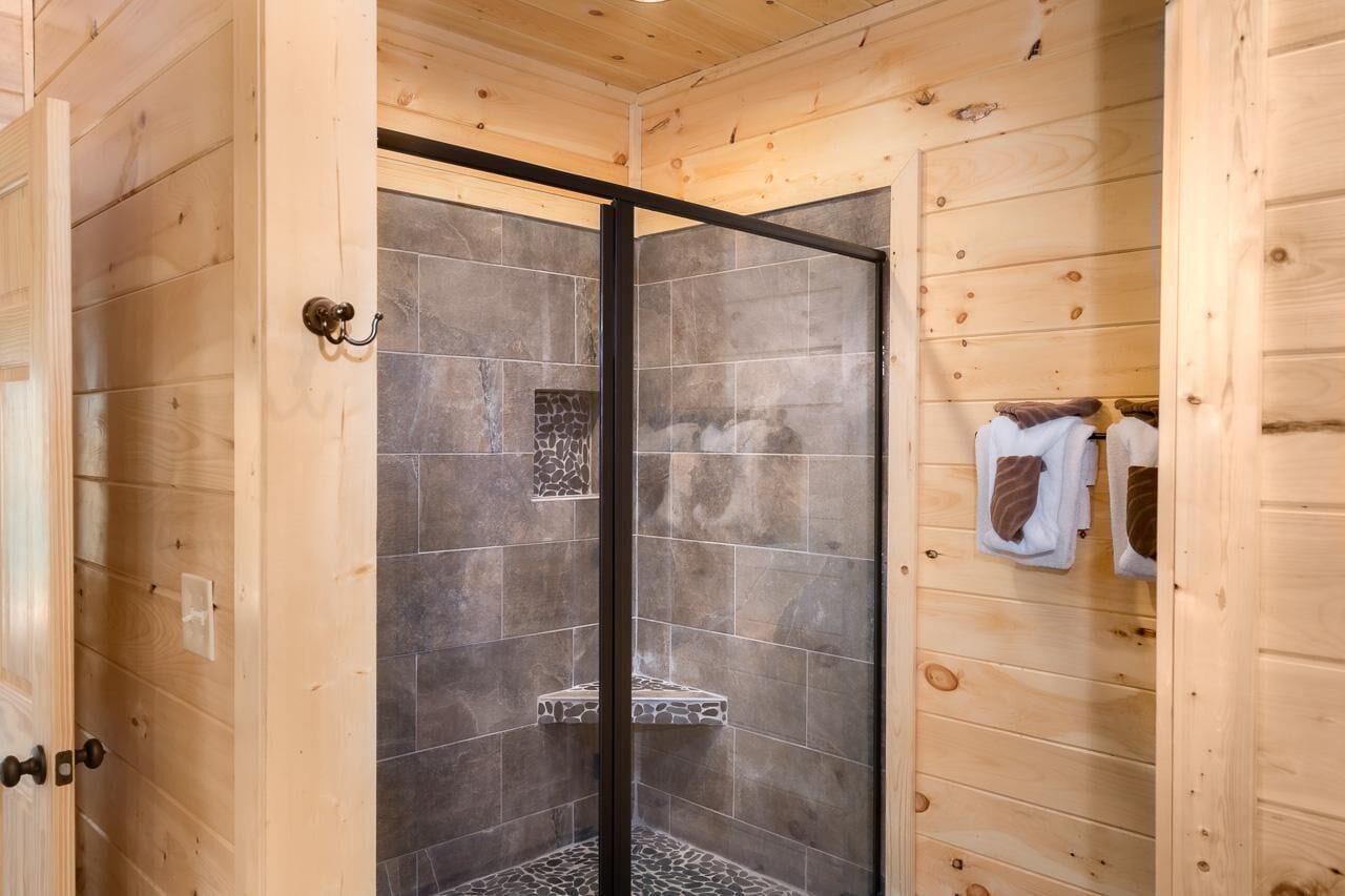 A wooden interior with a shower area featuring stone tiles and a bench.