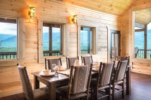 A wooden cabin with a dining table set for six, large windows, and a view of the mountains. - Southern Skies (Gatlinburg)