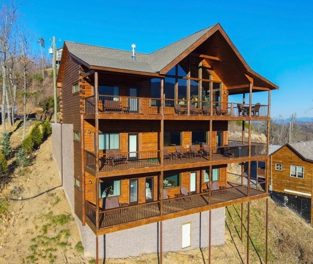 A multi-story wooden cabin with balconies and large windows.