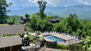 Ein Poolbereich mit Liegestühlen, einer Holzterrasse und Blick auf Berge.