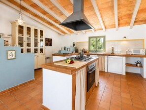 A kitchen with a central island, a stove, a sink, and a window. - Villa Sa Pleta - Three Bedroom Villa, Sleeps 6 (Mallorca)