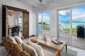 Un vaste espace de vie avec vue sur l’océan, un coin repas et un balcon aménagé avec du mobilier d’extérieur.