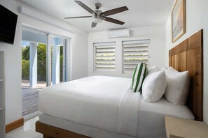 A bedroom with a bed, a ceiling fan, a wooden headboard, and a window with blinds.