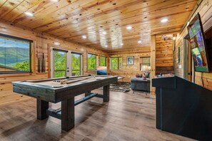 Ein Holzinterieur mit Poolbillard, Fenstern und Kicker.