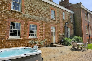 A brick building with a hot tub, outdoor seating, and a small garden area.
