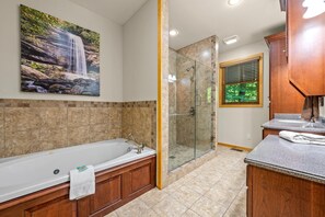 A bathroom with a bathtub, a glass-enclosed shower, and a window with blinds. - River Lodge (Sevierville)