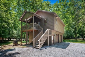 A two-story wooden cabin with a balcony, a staircase, and a gravel driveway. - River Lodge (Sevierville)