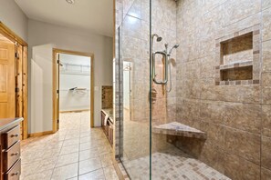 A bathroom with a glass-enclosed shower, a wooden cabinet, and a tiled floor. - River Lodge (Sevierville)