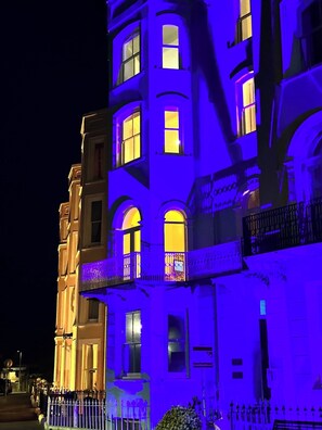 Ein mehrstöckiges Gebäude mit beleuchteten Fenstern und Balkonen bei Nacht.