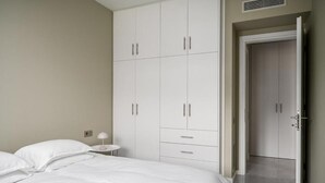 A bedroom with a bed, a nightstand, a wardrobe, and a door leading to another room. - Comme a la maison (Alepou)