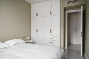 A bedroom with a bed, a nightstand, a wardrobe, and a door leading to another room. - Comme a la maison (Alepou)