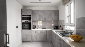 A modern kitchen with grey cabinets, a stainless steel refrigerator, an oven, and a sink. - Comme a la maison (Alepou)