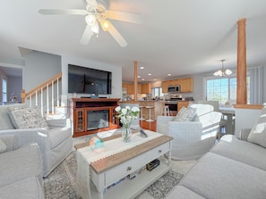 A spacious living room with a fireplace, a television, and a kitchen in the background. - Spacious 4BR Portland Retreat 4 King Beds + BBQ (Westbrook)