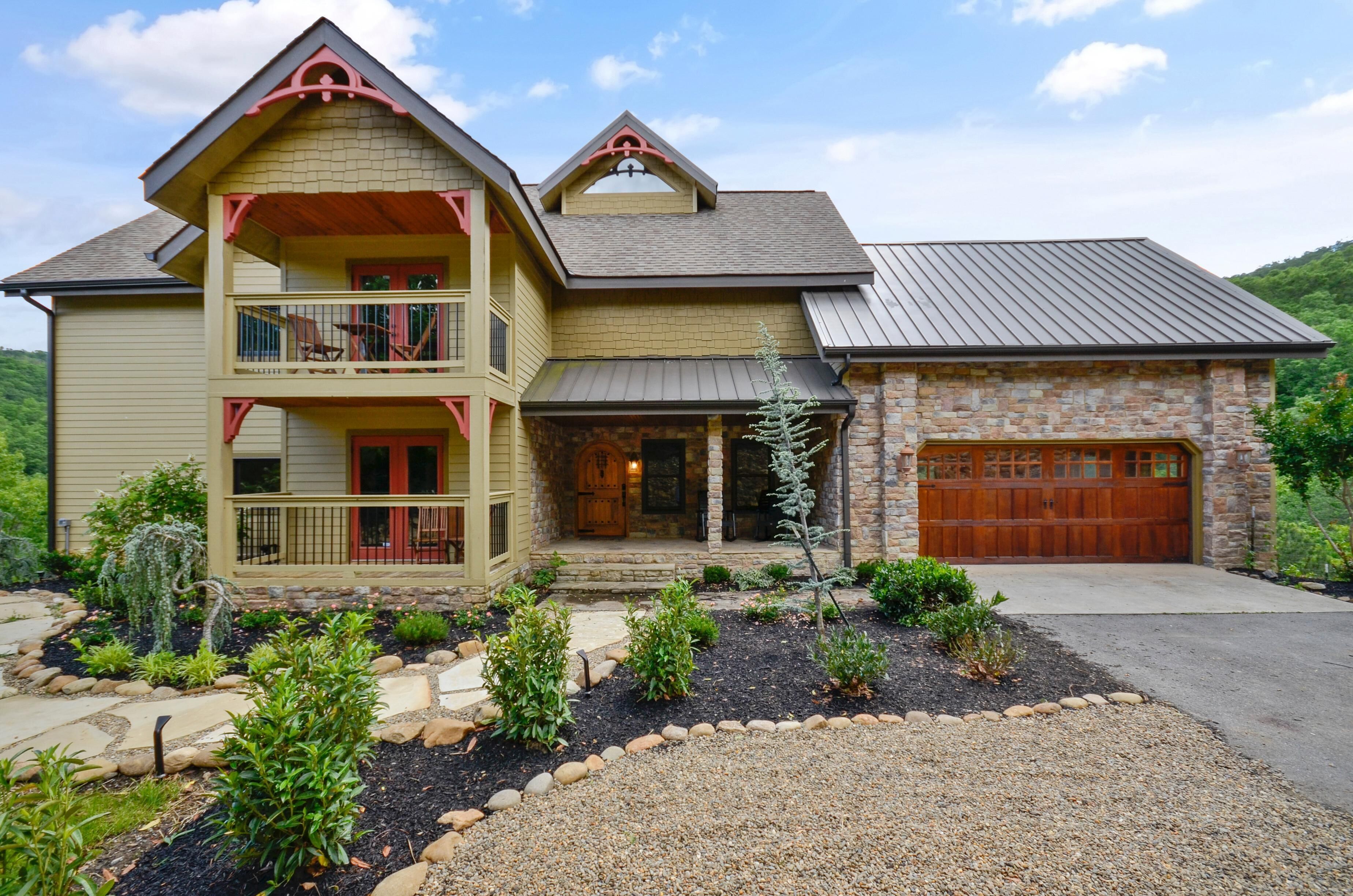A two-story house with a stone garage, a balcony, and a landscaped front yard.
