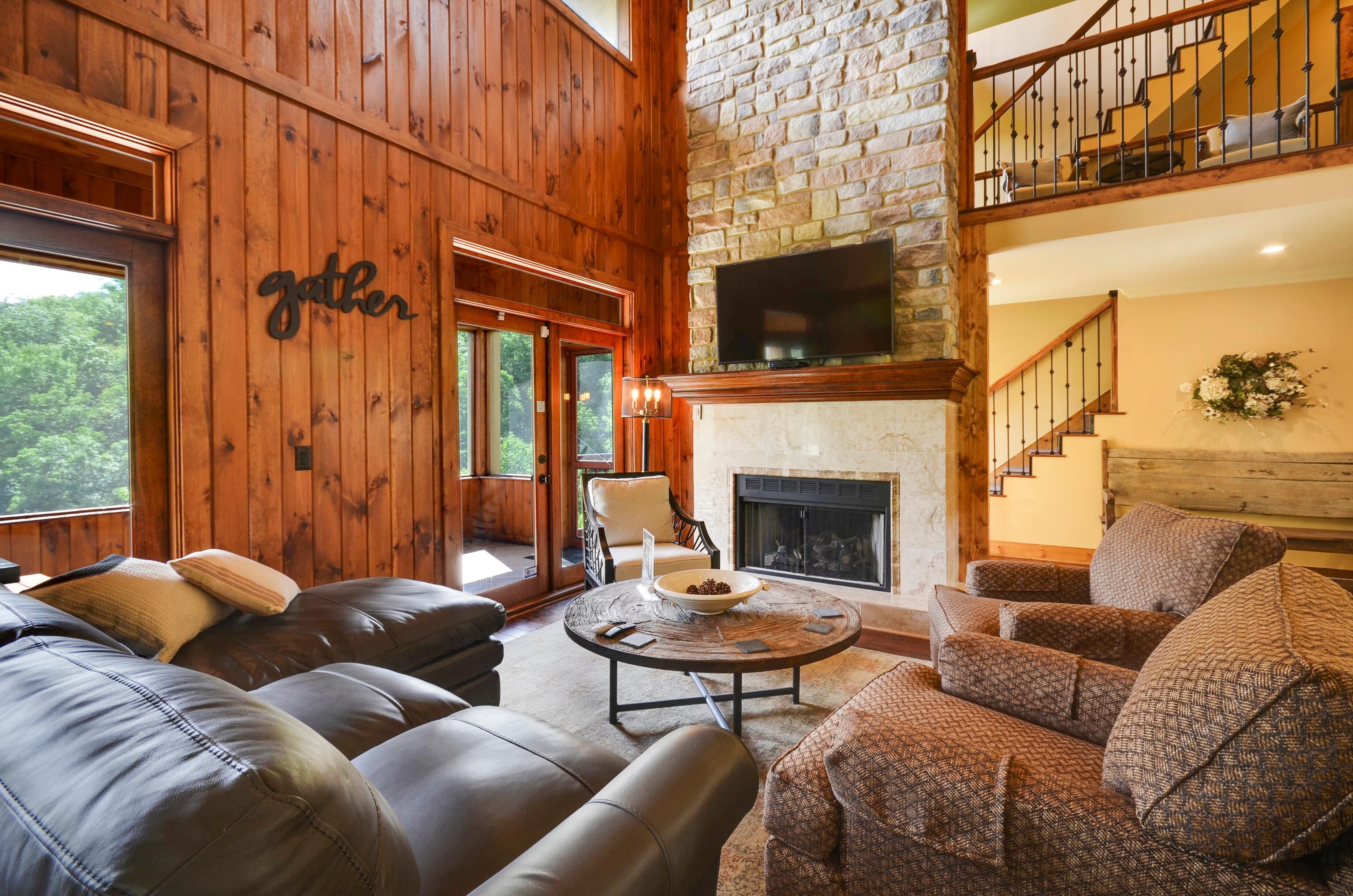 A cozy living room with a fireplace, leather sofas, and a stone wall.