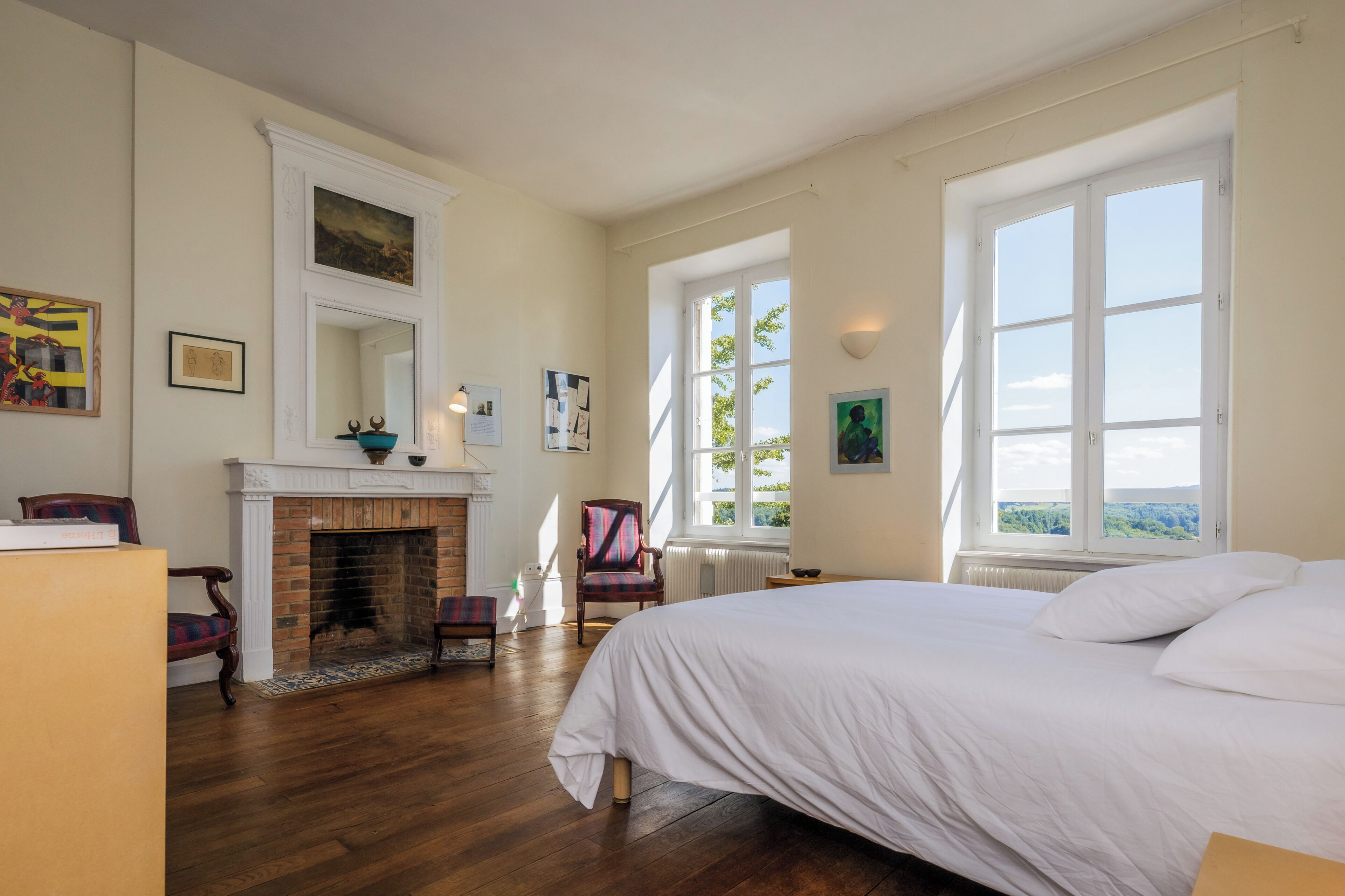 Un dormitorio con chimenea, una cama grande y vistas por la ventana.