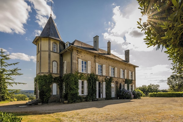 Un grand bâtiment historique, doté d’une tour imposante, de nombreuses fenêtres et d’un jardin bien entretenu.