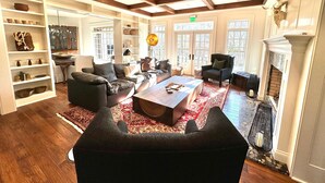 A spacious living room with a fireplace, leather sofas, a coffee table, and a large window. - Haven and Hearth (Gatlinburg)