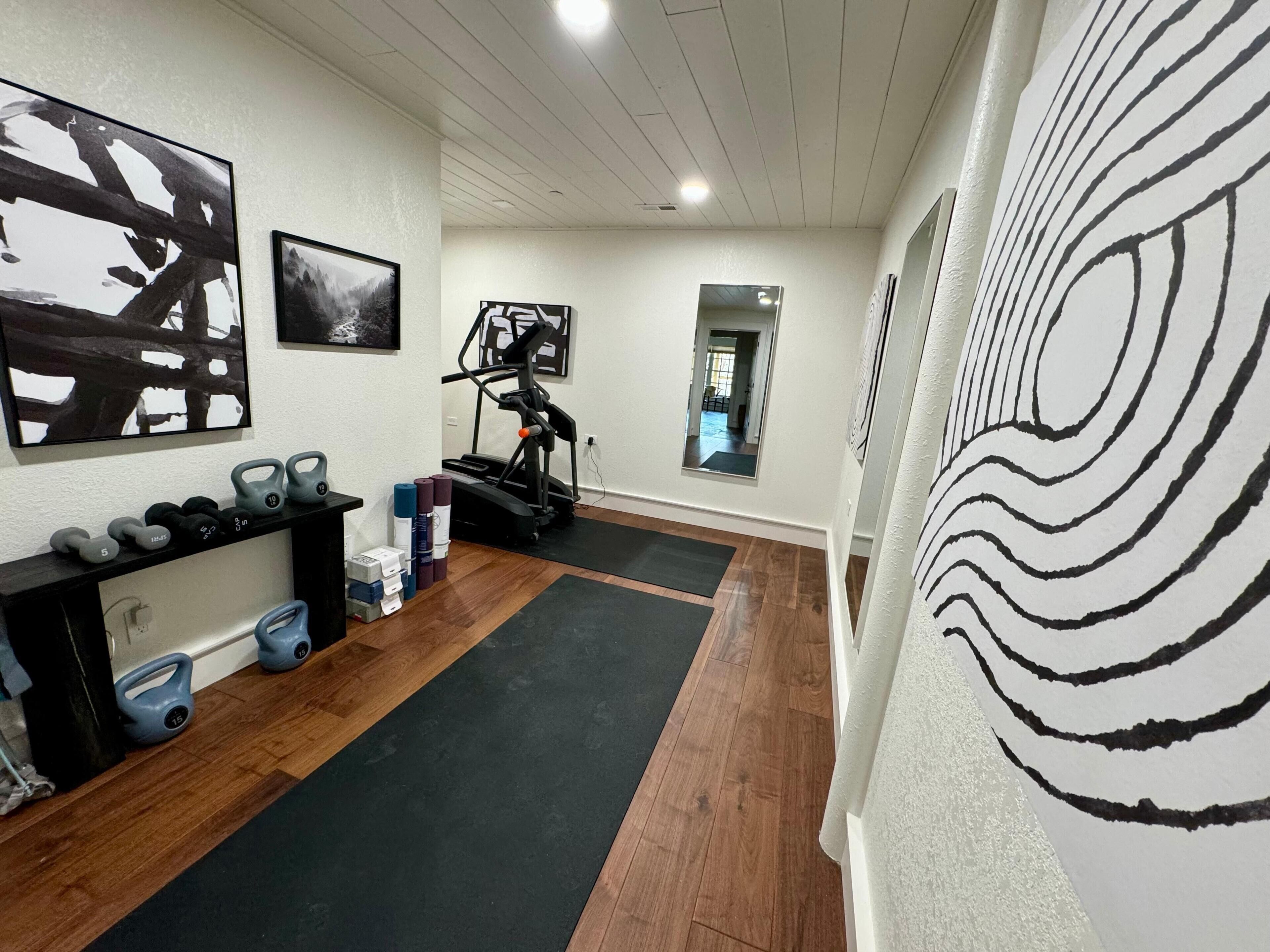 Ein Fitnessraum mit Trainingsgeräten, Laufband und Spiegel.