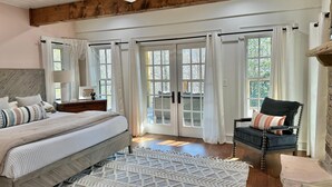 A bedroom with a bed, a chair, a wooden ceiling, and large windows. - Haven and Hearth (Gatlinburg)