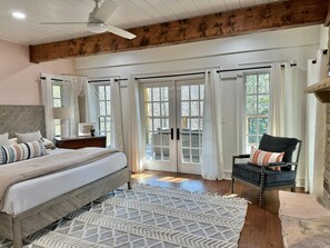 Ein Schlafzimmer mit einem Bett, einem Sessel, einer Holzbalkendecke und großen Fenstern.