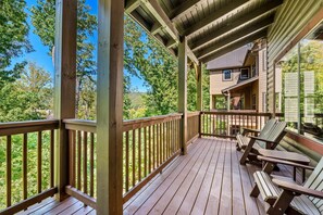 Eine Holzterrasse mit Geländer, einem überdachten Bereich und Blick auf ein Haus mit Fenster und Tür.