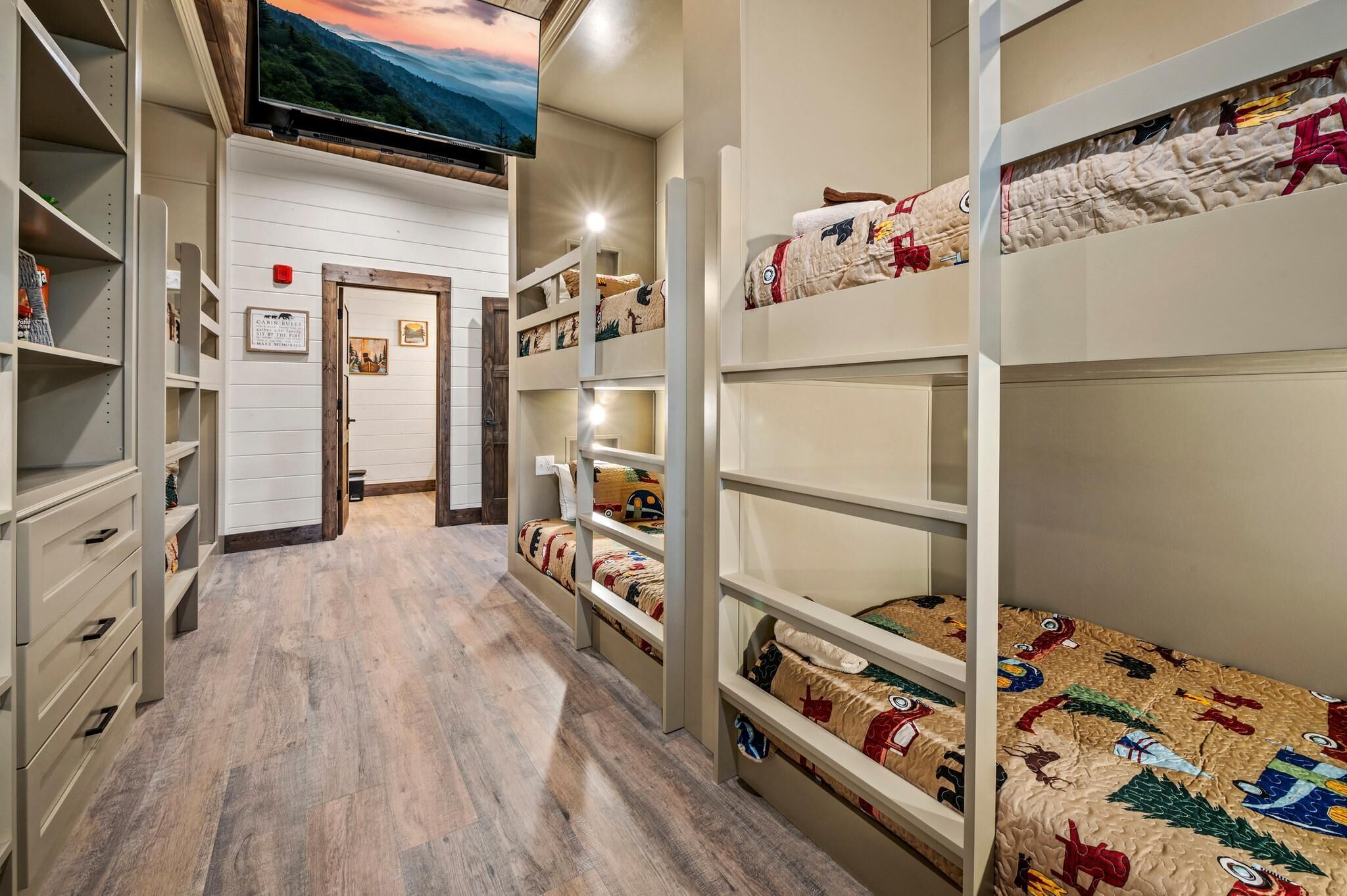 A hotel room with bunk beds, a television, and a wooden floor.