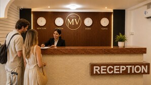 Un mostrador de recepción de hotel con relojes que marcan la hora en Nueva York, Londres, Dubái y Tokio.