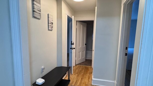 Un pasillo con un banco, un tapete y una puerta que da a otra habitación.