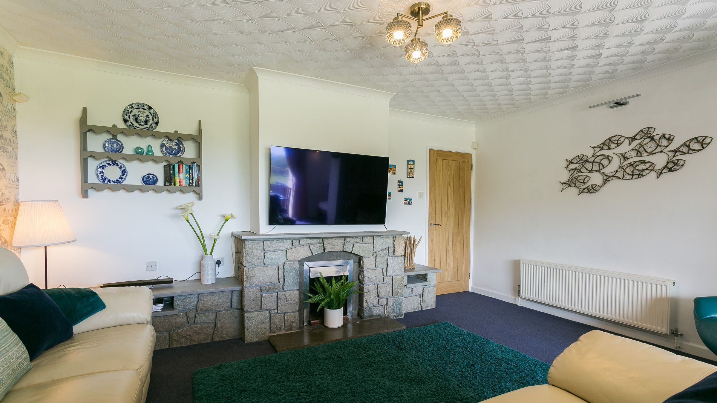 A living room with a fireplace, a television, and a decorative wall piece.