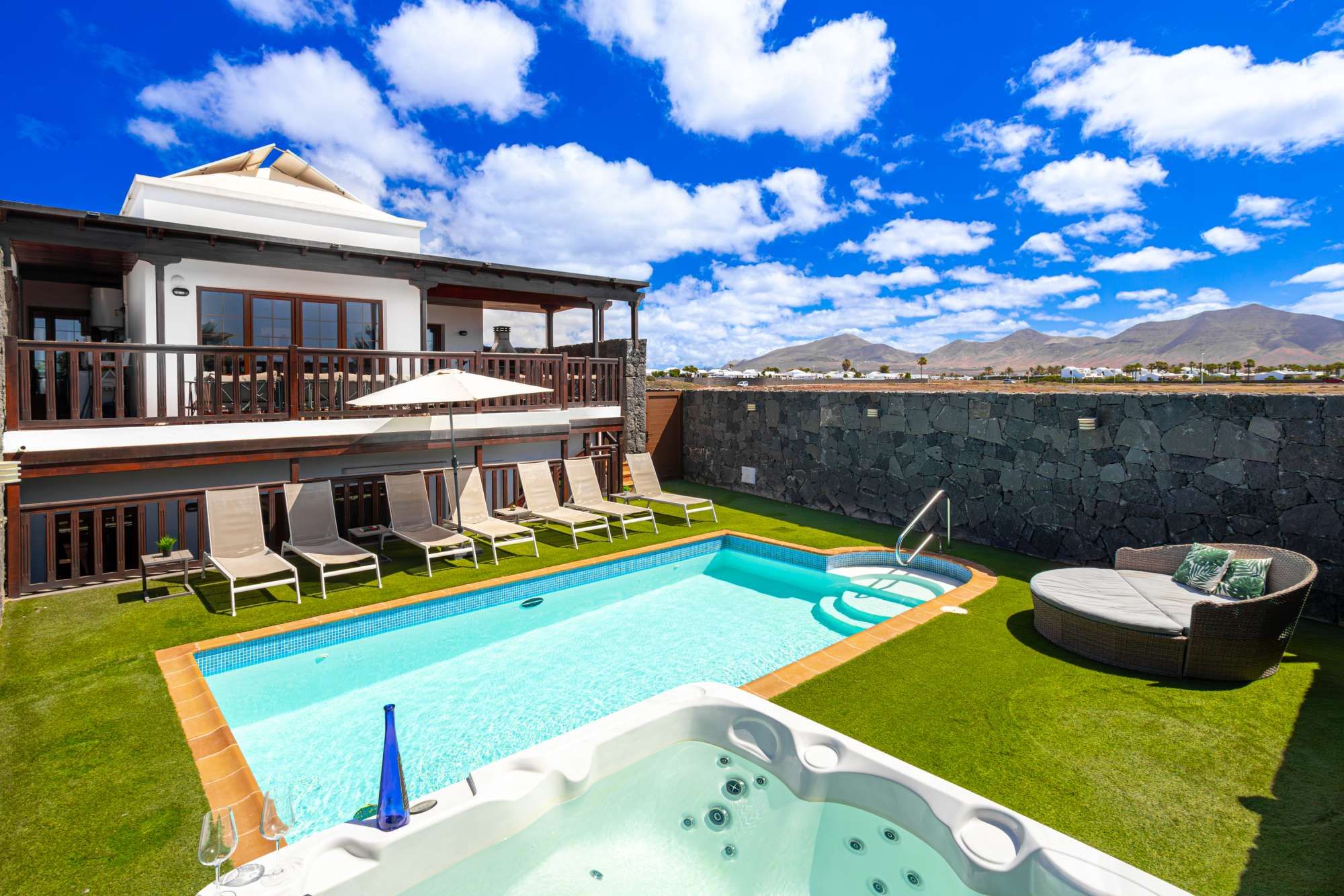 Un espace piscine aménagé sur le toit, avec un jacuzzi, des chaises longues et une vue sur les montagnes.