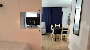 Hotellihuone, jossa on sänky, työpöytä tietokoneella, tuoli ja ruokapöytä tuoleineen.