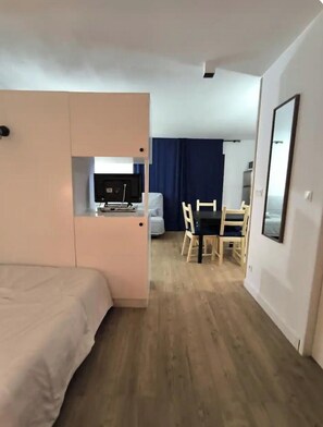 Ein Hotelzimmer mit einem Bett, einem Schreibtisch mit Computer, einem Sessel und einem Esstisch mit Stühlen.